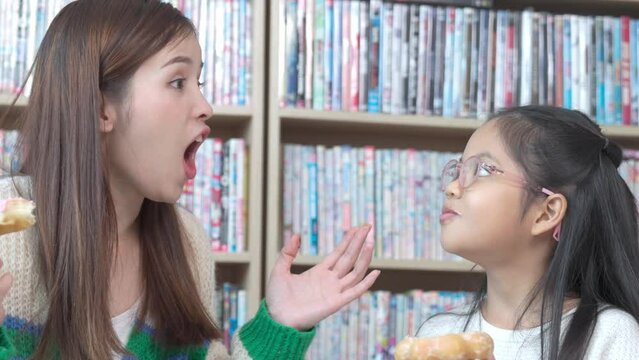 Asian teacher and children student taking break having fun while eating donuts.