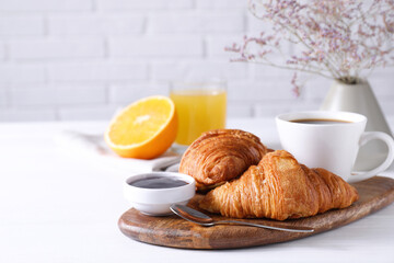 Tasty breakfast. Cup of coffee, jam and croissants on white wooden table, space for text