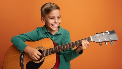 Obraz premium Joyful child playing guitar isolated on flat orange background with copy space. Creative banner for children's music school 