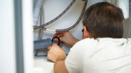 Plumber changes gasket in plumbing pipes sewerage in kitchen sink. Plumbing pipe repair. Removing...