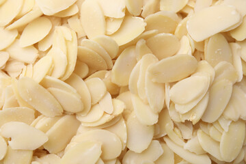 Fresh almond flakes as background, top view