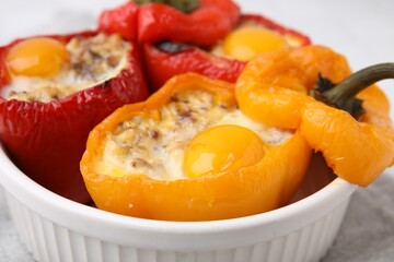 Delicious stuffed peppers with eggs in bowl on white table, closeup