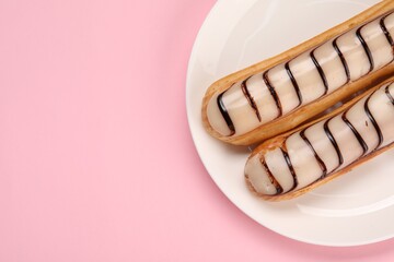 Delicious eclairs covered with glaze on pink background, top view. Space for text - obrazy, fototapety, plakaty