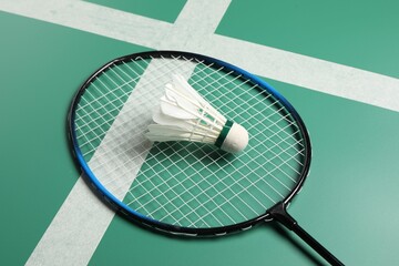 Feather badminton shuttlecock and racket on green table