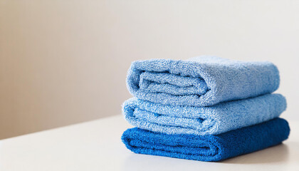 Stack of folded blue towels on table, light wall on background. Home laundry. Housekeeping concept