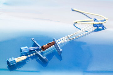 Triple lumen short-term central venous catheter with three infusion channels reflected on blue...