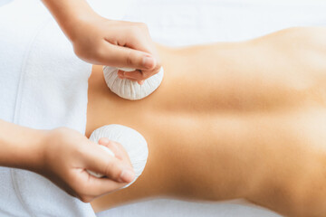 Hot herbal ball spa massage body treatment, masseur gently compresses herb bag on woman body....