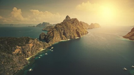 Sunset at tropical island El Nido at blue ocean bay. Sun shine aerial view. Nobody wild nature scenery at amazing tropic mountains islet of Palawan, Philippines archipelago. Cinematic summer vacation