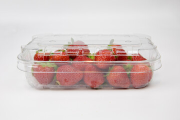 disposable plastic containers and lids on a white background. strawberries are packaged in a...