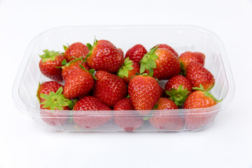 disposable plastic containers and lids on a white background. strawberries are packaged in a...