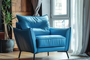 A blue leather chair sits in front of a window. The chair is positioned in a way that it is facing the window, allowing the sunlight to shine on it. The room has a modern and stylish feel