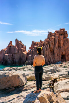 Woman and dog enjoying the rocky coast of Sardinia, Rocce Rosse