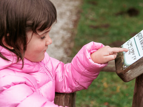 Young girl reading an information sign outdoors