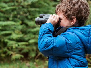 Young boy exploring nature with binoculars