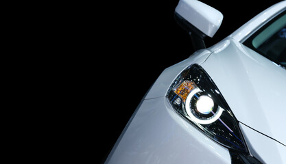 Close-up front right eyesight headlight with LED xenon light of white luxury modern car on black colour background and left copy space for text or message