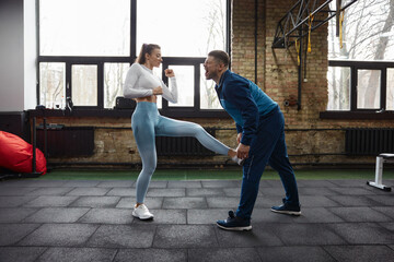 Young skilled woman practicing kicks during mma lesson with instructor