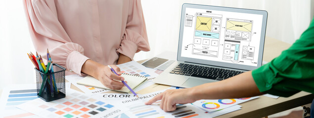 Cropped image of interior designer presents color from color swatches while laptop displayed...