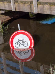 Bicycle traffic prohibited sign under a bridge in a water canal.
