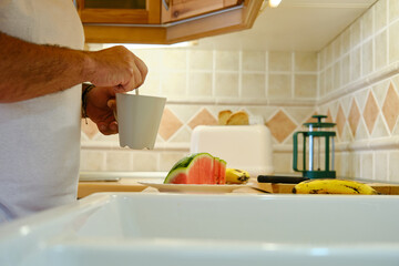 Unrecognizable man stirring coffee in mug with spoon