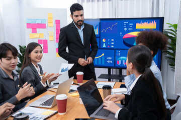 Businessman presenting data analysis dashboard display on TV screen in modern meeting for marketing...