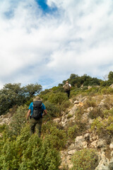 Obraz premium Back view of hikers walking along rocks in the mountain. 