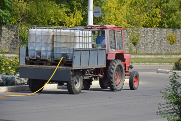 tractor with water tanks. watering flowers and plants on city streets. caring for the environment and beauty of one s hometown