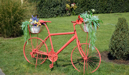 Fototapeta na wymiar decorative bicycle with baskets of flowers. decoration of lawns in city parks and squares. landscape design and decorations. place for a photo. beauty in nature