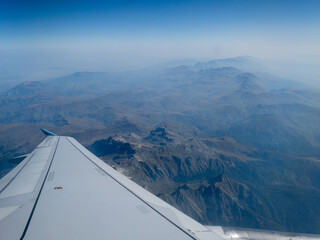 Fl&uuml;gel eines flugzeuges &uuml;ber ein gebirge mit wolken 