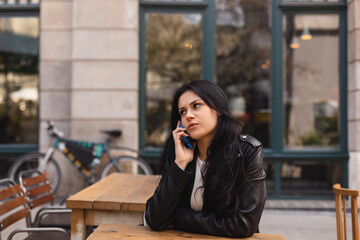 Confused puzzled brunette woman in casual clothes, sits in cafe, have call conversation smartphone, looks questioningly, unhappy, ridiculous. Girl getting surprising bad news, annoyed woman.