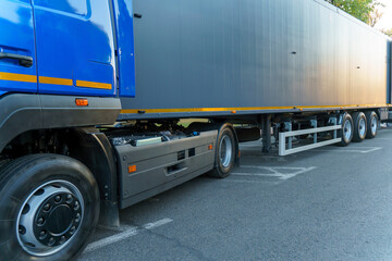 A new truck with a trailer on the road. Details of the truck in close-up. New headlights and wheels of the car. The concept of cargo transportation - obrazy, fototapety, plakaty