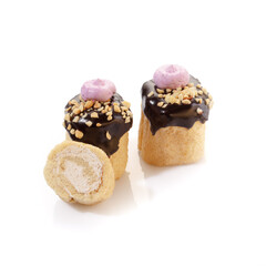 Delicate vanilla sponge rolls filled with buttercream and candied citrus fruits topped with nut crumbs and yellow icing, presented isolated on white background