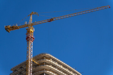 Yellow cranes on the background of multi-storey buildings under construction and blue sky....