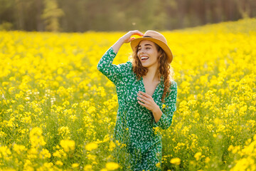 Fototapeta premium Beautiful woman in bright dress in rapeseed field. Nature, vacation, relax and lifestyle. Summer landscape.