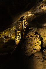 Prometheus karst cave, illuminated by colorful lights, stalactites and stalagmites. Vertical photo
