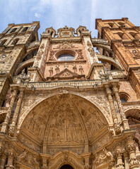 Vista vertical de la Catedral de Santa María de Astorga, monumento nacional de España, con filigranas, decoraciones, y estatuas en la fachada, verano 2021