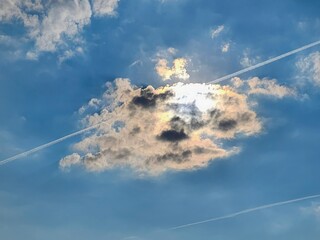 A magnificent cumulus cloud with a radiant silver lining drifts in a vivid blue sky, basking in the...