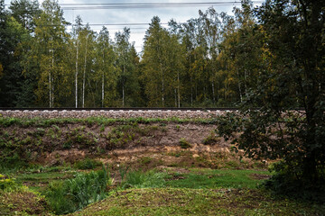 View of the railway track on a high embankment in the forest on a cloudy summer day.