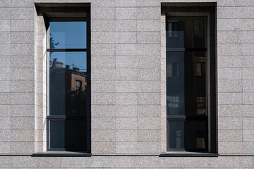 Two rectangular windows with gray, made in a modern style with the reflection of the sky and houses on the glass, against the background of a gray wall. From the series Window of the World.