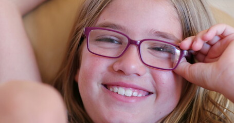 Little girl face wearing glasses watching movie at home smiling