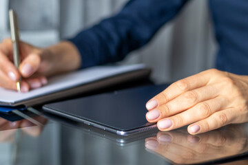 Close up shot of the woman with beautiful hands in the business attire, working on the tablet in...