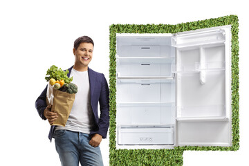 Young man holding a grocery bag and leaning on a green eco friendly fridge