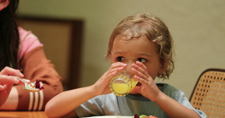 Toddler little boy drinking orange juice