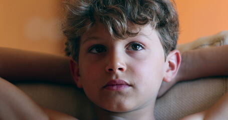 Young boy face in living room sofa watching movie screen at home