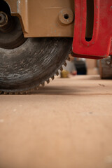 A close up of a circular saw blade with a red handle. Concept of precision and focus, as the viewer...