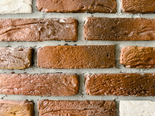 Brick wall with brown, white bricks close-up. The texture of the bricks is rough and uneven, with visible cracks and chips and cement between the bricks