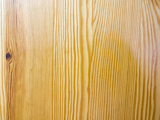 Close-up of a smooth yellow piece of wood with a small round knot in the center. The wood grain is...
