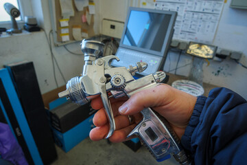 a paint spray gun is held in the hand