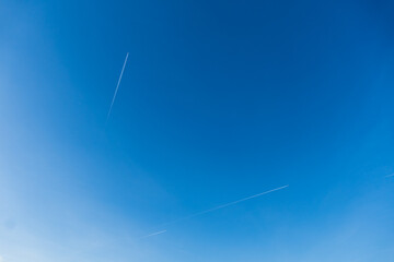 Two airplanes with white contrail in blue sky.