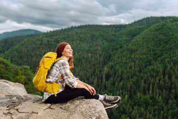 Young tourist woman  on top of a mountain. Scenery of the majestic mountains. Active lifestyle.