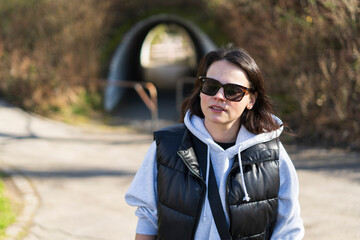 Portrait of a young woman in sunglasses standing on a road.